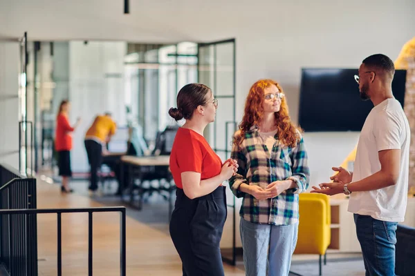 stock image Group of business colleagues, including an African American businessman, engage in a conversation about business issues in the hallway of a modern startup coworking center, exemplifying dynamic