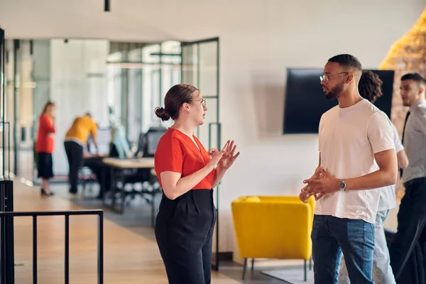 stock image Young business colleagues, including an African American businessman, engage in a conversation about business issues in the hallway of a modern startup coworking center, exemplifying dynamic problem