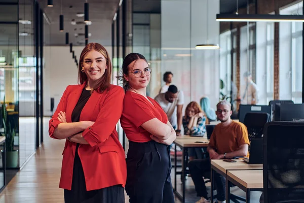 Group of determined businesswomen confidently pose side by side in a modern startup coworking center, embodying professionalism and empowerment.