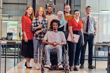 Genç iş adamlarından oluşan çeşitli bir grup, modern bir girişim olan cam kaplı bir ofiste, tekerlekli sandalyedeki bir kişi, bir Afrikalı Amerikalı genç adam ve bir tesettür ile bir araya geliyor.