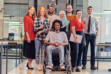 Genç iş adamlarından oluşan çeşitli bir grup, modern bir girişim olan cam kaplı bir ofiste, tekerlekli sandalyedeki bir kişi, bir Afrikalı Amerikalı genç adam ve bir tesettür ile bir araya geliyor.