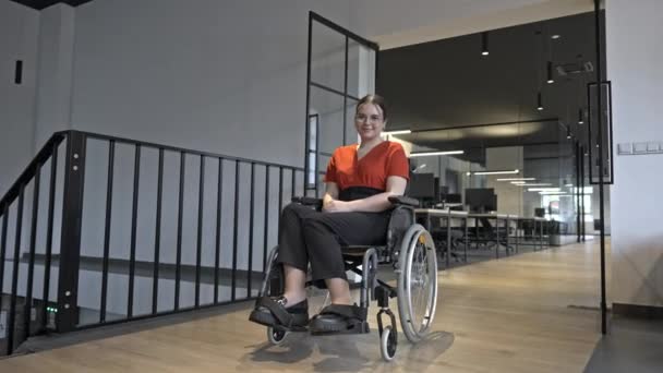 車椅子の現代の若い実業家は グラスウォールのオフィスを持つ包括的なワークスペースに囲まれ ビジネスの世界で決意と革新を体現しています — ストック動画