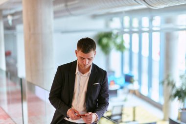 Gösterişli bir şirket ortamında, genç ve karizmatik yönetmen koridorda güven içinde yürüyor, dinamik liderliğini ve şirket içindeki başarısının devamını simgeliyor.