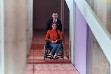 Bir şirket müdürü, iş arkadaşına tekerlekli sandalyede yardım ederek, farklı meslekdaşlarından oluşan ekiple birlikte çalıştıkları başlangıç ofislerine kadar rehberlik eder.