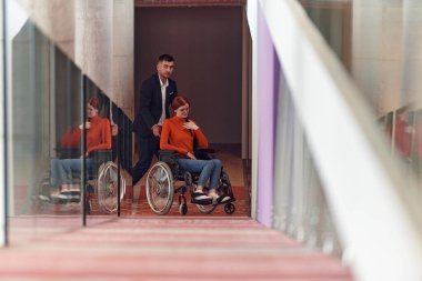 Bir şirket müdürü, iş arkadaşına tekerlekli sandalyede yardım ederek, farklı meslekdaşlarından oluşan ekiple birlikte çalıştıkları başlangıç ofislerine kadar rehberlik eder.