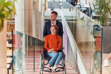 Bir şirket müdürü, iş arkadaşına tekerlekli sandalyede yardım ederek, farklı meslekdaşlarından oluşan ekiple birlikte çalıştıkları başlangıç ofislerine kadar rehberlik eder.