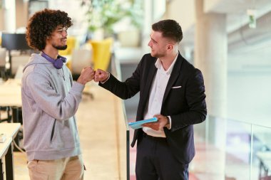 Modern bir ofis ortamında, Afrikalı bir Amerikalı işadamı ve yönetmeni güven içinde ellerini uzatarak bir iş sorununun başarılı bir şekilde çözülmesini sembolize ediyorlar.