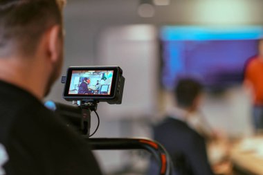 Bir kameraman, modern bir ofiste bir toplantıya liderlik eden bir yönetmeni filme alır..