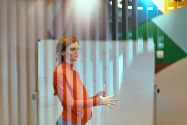 stock image A pregnant business woman with orange hair confidently presents her business plan to colleagues in a modern glass office, embodying entrepreneurship and innovation. 