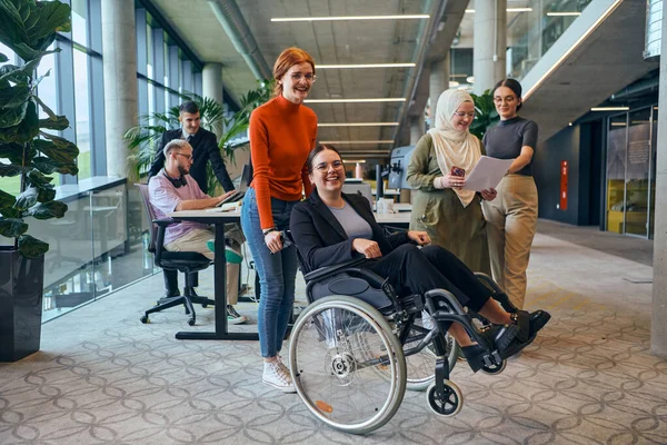 다양한 그룹의 비즈니스 동료들은 휠체어를 사용하는 동료들과 재미를 느끼며 직장에서 — 스톡 사진