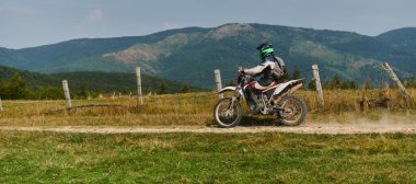 Profesyonel bir motokros sürücüsü heyecanlı bir şekilde motorsikletleriyle tehlikeli bir off-road orman yolu sürüyor.