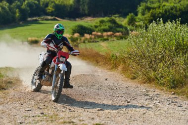 Profesyonel bir motokros sürücüsü heyecanlı bir şekilde motorsikletleriyle tehlikeli bir off-road orman yolu sürüyor.