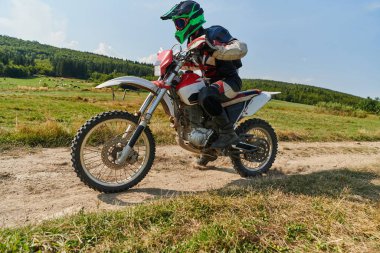 Profesyonel bir motokros sürücüsü heyecanlı bir şekilde motorsikletleriyle tehlikeli bir off-road orman yolu sürüyor.