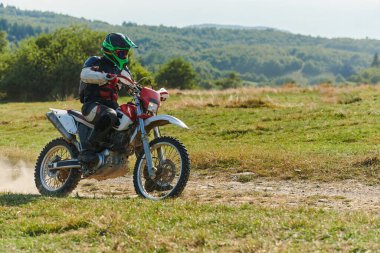 Profesyonel bir motokros sürücüsü heyecanlı bir şekilde motorsikletleriyle tehlikeli bir off-road orman yolu sürüyor.