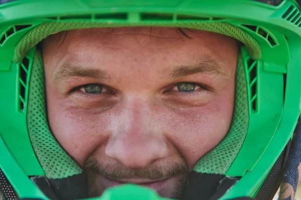The determined face of a professional motocross rider, adorned with a protective helmet, reflects unwavering focus and readiness for an adrenaline-fueled adventure