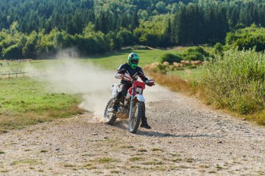 Profesyonel bir motokros sürücüsü heyecanlı bir şekilde motorsikletleriyle tehlikeli bir off-road orman yolu sürüyor.