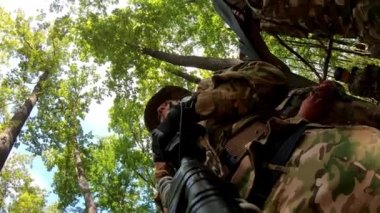 Silah banyosundaki kamera. Miğferli askeri keskin nişancı ormandaki düşmana saldırıyor. Özel kuvvetler olarak bir silahın içinde olmak için yakın plan bir çekim. Yüksek kalite 4k görüntü