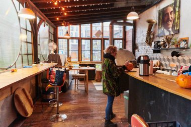 Askeri üniformalı modern sarışın bir kadın Cadılar Bayramı gecesi için bıçakla ürkütücü balkabakları oyuyor.. 