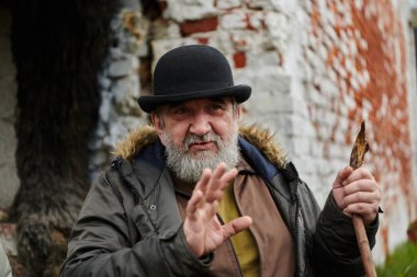 Sakallı ve şapkalı yaşlı bir adam tutkulu bir şekilde diğerlerine geleneksel değerleri ve kültürel bilgeliği aktarıyor, miras koruma ve hikaye anlatmanın özünü somutlaştırıyor.