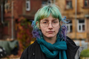 Evinin önündeki parkta çekilen çarpıcı mavi saçlı, büyüleyici bir genç kız portresi karizmatik ve stil sahibi kişiliğini doğal bir açık hava karakterine karşı sergiliyor.