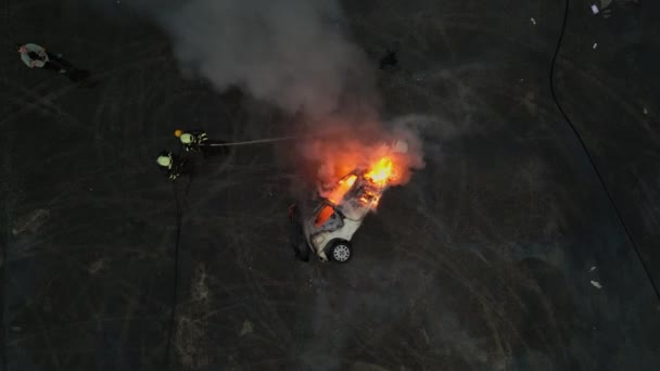 彼らの勇気と英雄的な努力を披露する 彼らの装置と消防車を使用して車の火災を消すために一緒に働くプロの消防士のグループの航空無人機の映像 — ストック動画