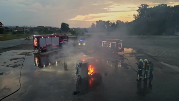 彼らの勇気と英雄的な努力を披露する 彼らの装置と消防車を使用して車の火災を消すために一緒に働くプロの消防士のグループの航空無人機の映像 — ストック動画