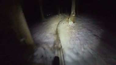 Bir grup arkadaş kış gecesi kaygan bir patikada yokuş aşağı dağ bisikleti sürerken birinci şahıs bakış açısıyla POV göğüs sabit video montajı taze karla birlikte..