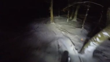 Bir grup arkadaş kış gecesi kaygan bir patikada yokuş aşağı dağ bisikleti sürerken birinci şahıs bakış açısıyla POV göğüs sabit video montajı taze karla birlikte..
