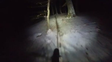 Bir grup arkadaş kış gecesi kaygan bir patikada yokuş aşağı dağ bisikleti sürerken birinci şahıs bakış açısıyla POV göğüs sabit video montajı taze karla birlikte..