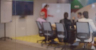 Turuncu saçlı hamile bir iş kadını, girişimcilik ve yenilikleri somutlaştıran modern cam ofisindeki meslektaşlarına iş planını gururla sunar.. 