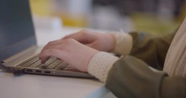 Modern bir ofiste dizüstü bilgisayarda çalışan iş kadını parmağı videosunu kapat, çeşitli işyerlerindeki kapsayıcılığı ve profesyonelliği vurgula