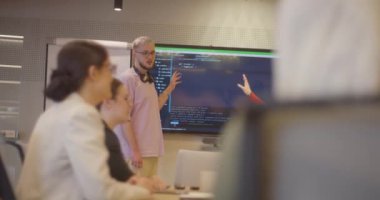 Modern cam bir ofiste çeşitli uzmanlardan oluşan bir ekip, dikkatle bir meslektaşlarını dinliyor, işbirliği ve yenilikleri teşvik ediyorlar.