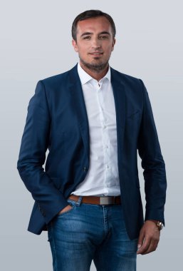 Genç, odaklanmış Avrupalı iş adamı. Koyu renk saçlı, sıradan iş kıyafetleri giyen, gri arka plan stüdyo çekimlerinde izole edilmiş bir adamın ön görüntüsü.. 