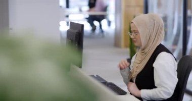 Modern bir ofiste, başörtüsü takan Müslüman bir girişimci güvenli ve gayretli bir şekilde bilgisayarında oturur, kararlılığı, yaratıcılığı ve iş dünyasının güçlendirilmesini somutlaştırır.. 