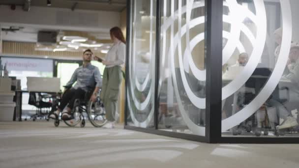 大規模な現代企業では 車椅子の決意されたビジネスマンが廊下をナビゲートし 企業の世界でエンパワーメントと寛容さを体現します — ストック動画