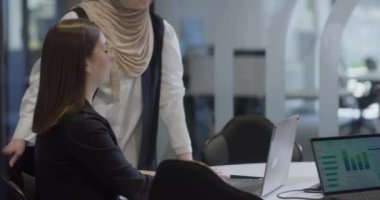 Bir tanesi tesettür takan çeşitli iş kadınlarından oluşan bir grup, bir dizüstü bilgisayara odaklanırken, tartışmalar ve problem çözme, göstermelik profesyonellik, takım çalışması ve etkili bir çalışma ile işbirliği yapıyor.