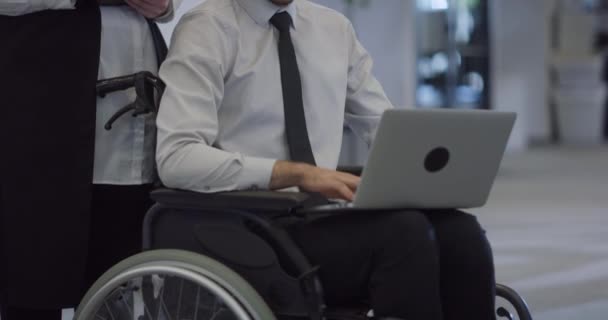 車椅子の熟考ディレクターは 現代のオフィスでラップトップで作業し プロフェッショナリズム 企業環境の包括的でアクセスしやすい性質を体現しています — ストック動画