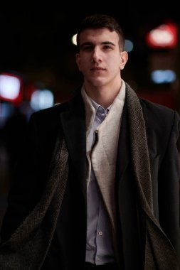 Gülümseyen Meedle Eastern adamı modern ofis binasının yakınındaki caddede yürüyor, serbest çalışan işadamı geceleri işlek şehir caddesinde elinde cep telefonuyla diğer tarafa bakıyor.