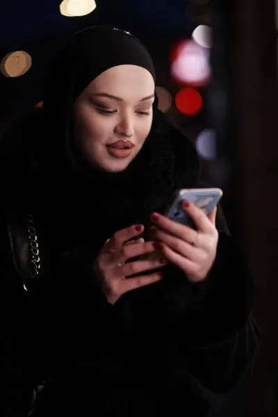 美しくエレガントなヨーロッパのイスラム教徒ヒジャビービジネスレディー夜の都市街路で彼女の携帯電話とソーシャルメディアをチェック — ストック写真