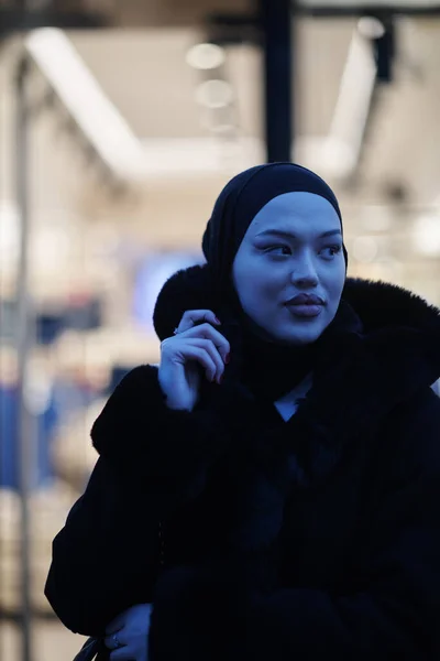 イスラム教徒の女性は 寒い冬の夜 バックグラウンドのボケ市灯でヒジャブを着用して都市街の通りを歩いています — ストック写真