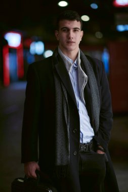 Gülümseyen Meedle Eastern adamı modern ofis binasının yakınındaki caddede yürüyor, serbest çalışan işadamı geceleri işlek şehir caddesinde elinde cep telefonuyla diğer tarafa bakıyor.