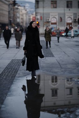 Soğuk bir kış gecesinde şehir caddesinde yürüyen Müslüman bir kadın arka planda Bokeh şehir ışıklarıyla tesettüre girmiş.