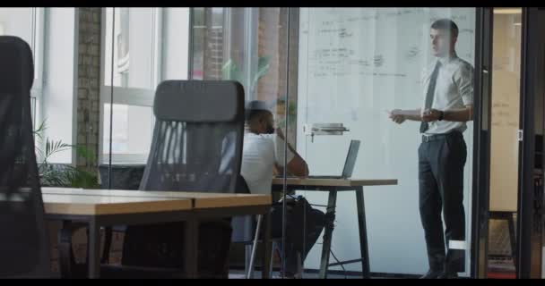 一位自信的主管在现代玻璃办公室向同事们解释工作计划和解决问题的方法 — 图库视频影像
