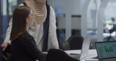 Bir tanesi tesettür takan çeşitli iş kadınlarından oluşan bir grup, bir dizüstü bilgisayara odaklanırken, tartışmalar ve problem çözme, göstermelik profesyonellik, takım çalışması ve etkili bir çalışma ile işbirliği yapıyor.