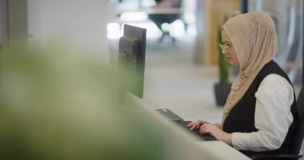 在一个现代化的办公室里 一个头戴头巾的穆斯林企业家自信而勤奋地坐在自己的电脑上 体现了商界的决心 创造力和力量 — 图库视频影像