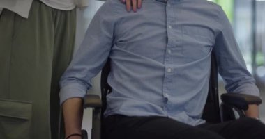 Büyük, modern bir şirkette, tekerlekli sandalyedeki bir işadamı bir koridorda dolaşır, kurumsal dünyaya güç ve kapsayıcılık katar.