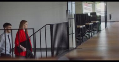 İki genç iş arkadaşı modern bir ofiste yürüyor ve çeşitli iş sorunları hakkında dinamik bir tartışmaya giriyorlar.