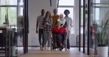 Genç iş adamlarından oluşan çeşitli bir grup, modern bir girişim olan cam kaplı bir ofiste, tekerlekli sandalyedeki bir kişi, bir Afrikalı Amerikalı genç adam ve bir tesettür ile bir araya geliyor.