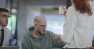 Modern bir iş kadını, modern bir ofiste kahve molası verirken meslektaşlarıyla canlı bir konuşma yapar. Etkili iletişim, takım çalışması ve iş hayatını örnek alır.