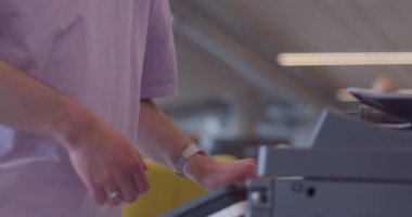 Modern, sarı saçlı bir adam, ileri düzey ofis teknolojisi ve iş akışı yönetimi sunan, geniş, çağdaş bir ofiste yüksek teknolojili bir kağıt yazıcısını etkili bir şekilde çalıştırıyor.. 